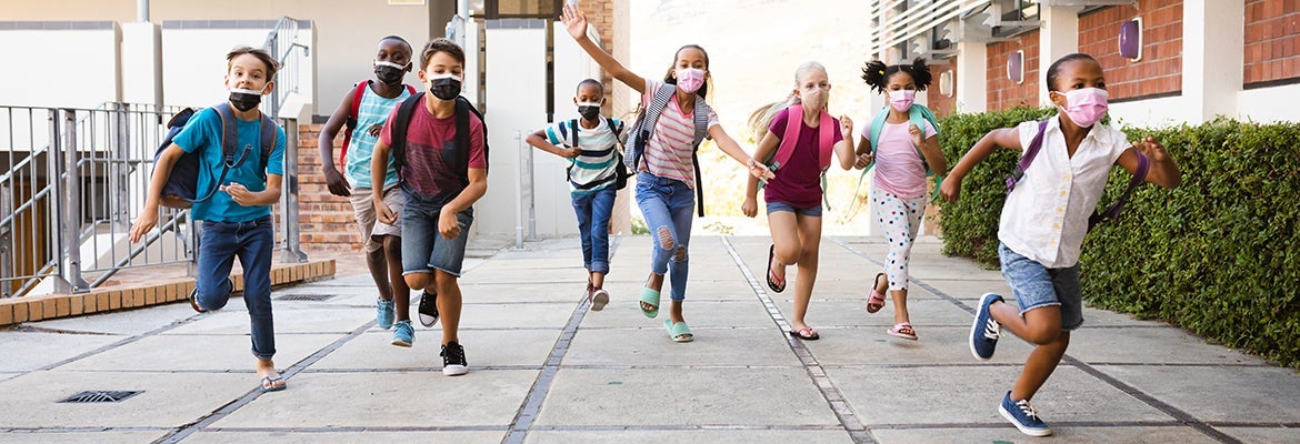 Group of diverse students wearing face masks running