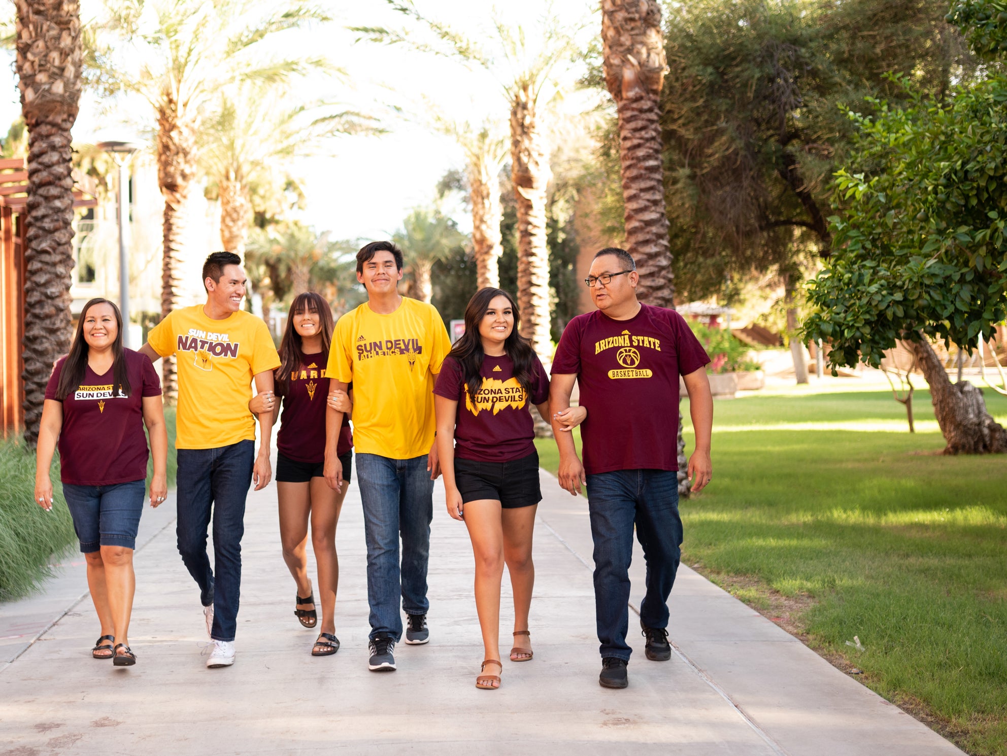 A group of students walking on campus wearing ASU shirts with their parents
