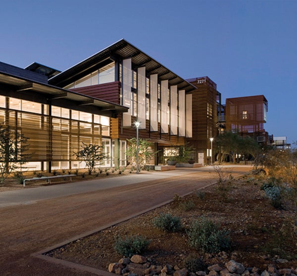 A modern building with glass and wood facade on the Polytechnic campus at twilight. 