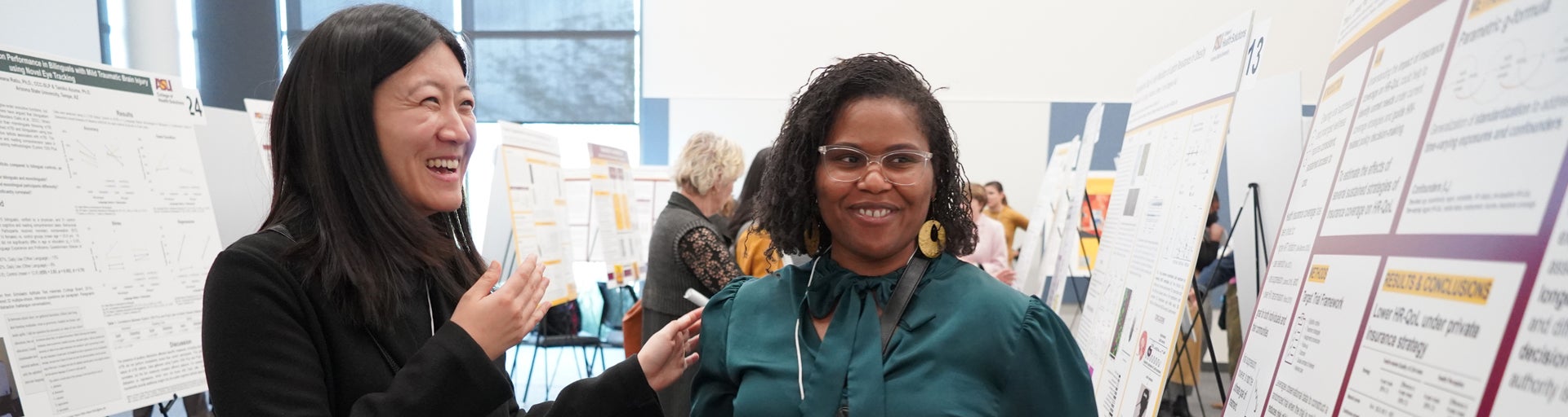 Two women smiling at a poster presentation event.