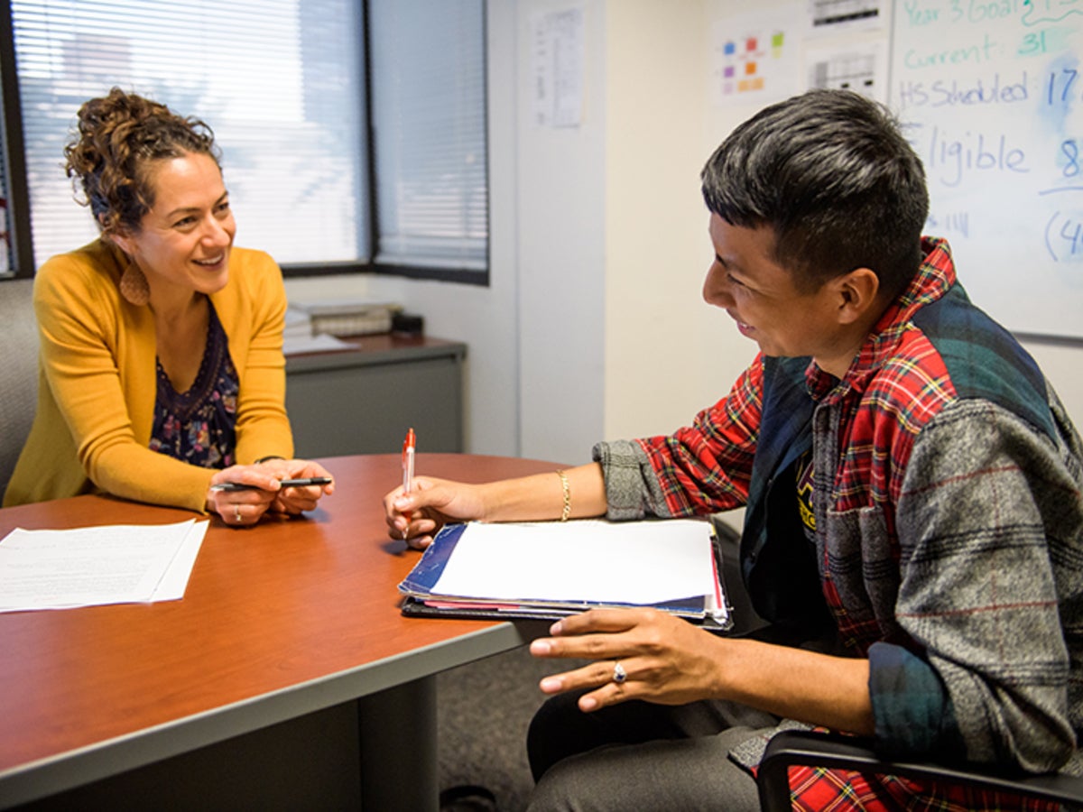 ASU advisor and student having a discussion at a table in an office setting.