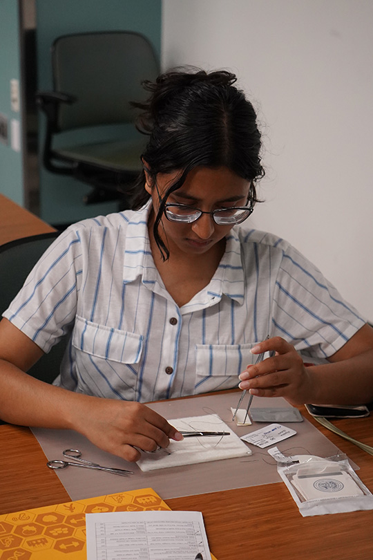 Students participate in a hands-on classroom workshop, engaging with medical supplies at their desks while instructors offer guidance and support throughout the session.