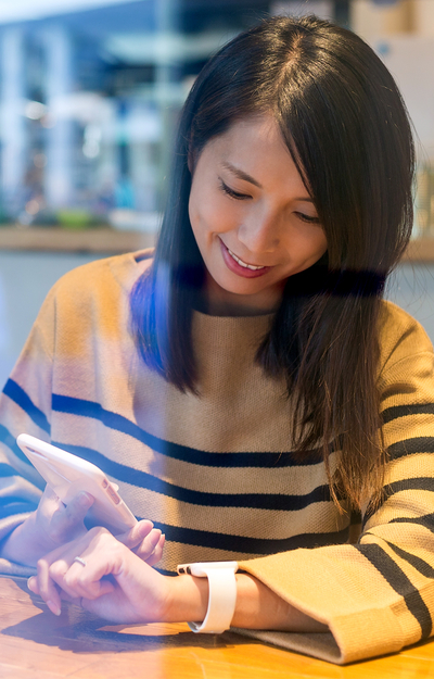 Woman in a striped sweater using her smartphone, with a smartwatch on her wrist.